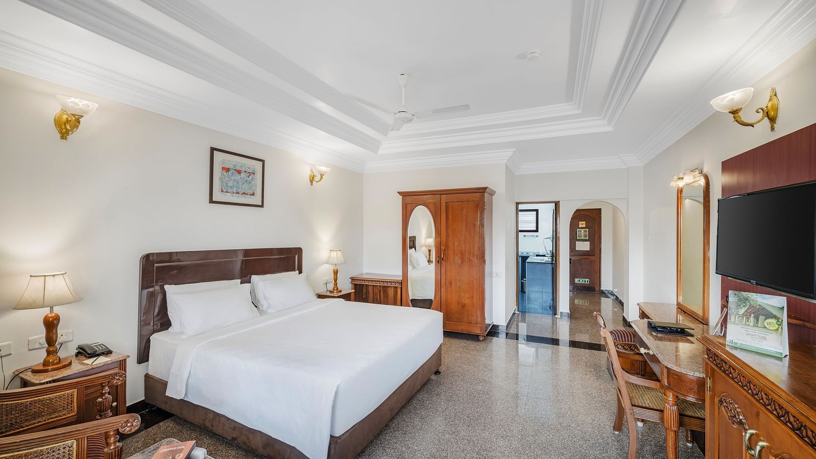 An image of a room with a queen size bed, bed side table, lamps, flat screen TV, modern amenities with minimal decoration - GReaT Trails River View Resort Thanjavur By GRT Hotels