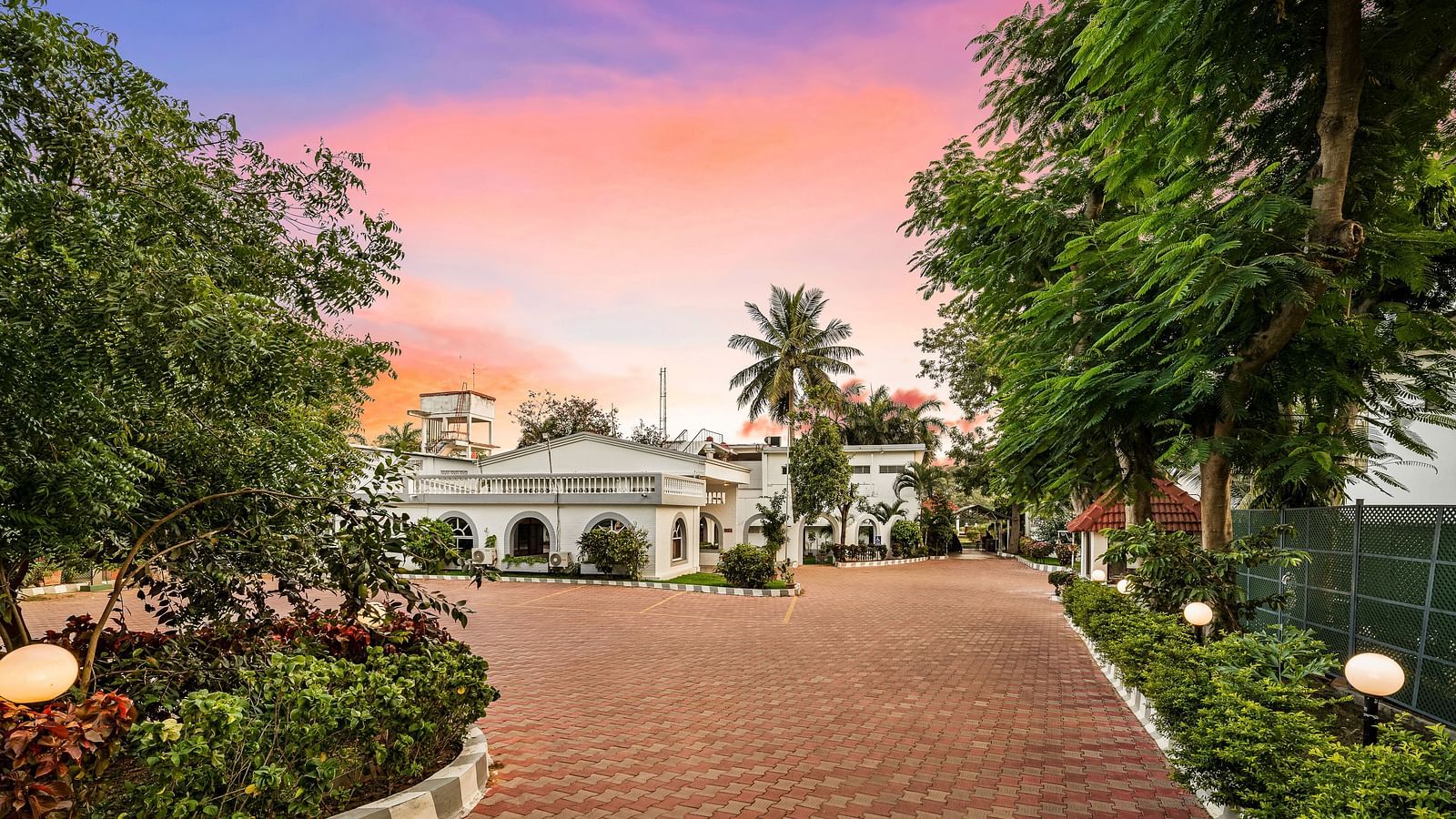A facade image of GReaT Trails River View Resort Thanjavur By GRT Hotels surrounded by lush greenery