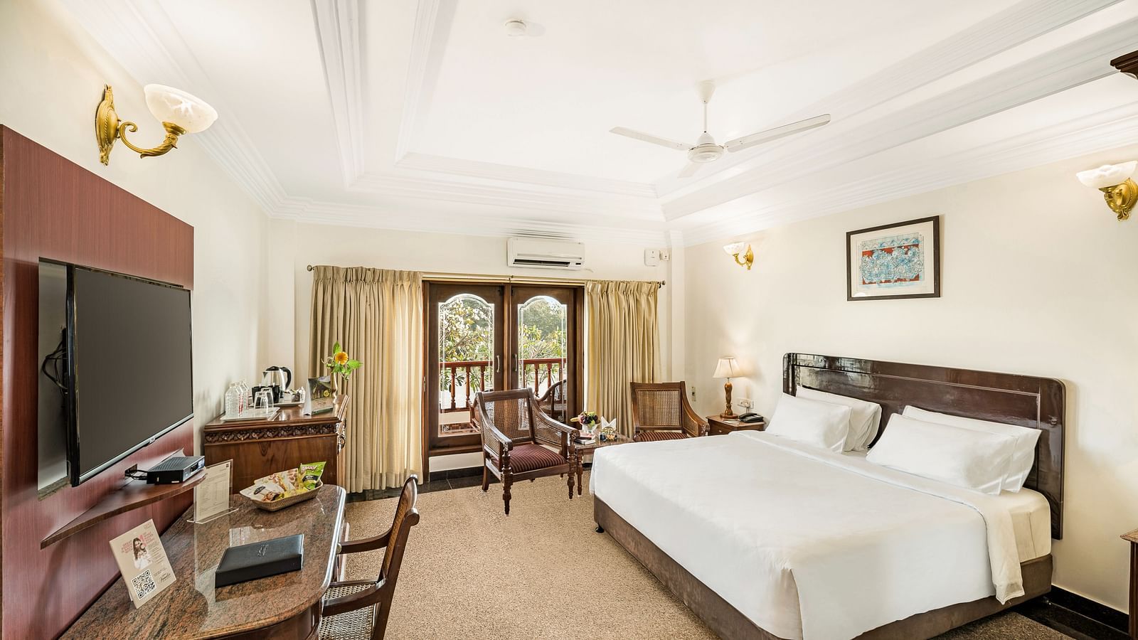 A image of a room with a king size bed, bed side table, flat screen TV, ceiling fan, and a work desk with chair - GReaT Trails River View Resort Thanjavur By GRT Hotels