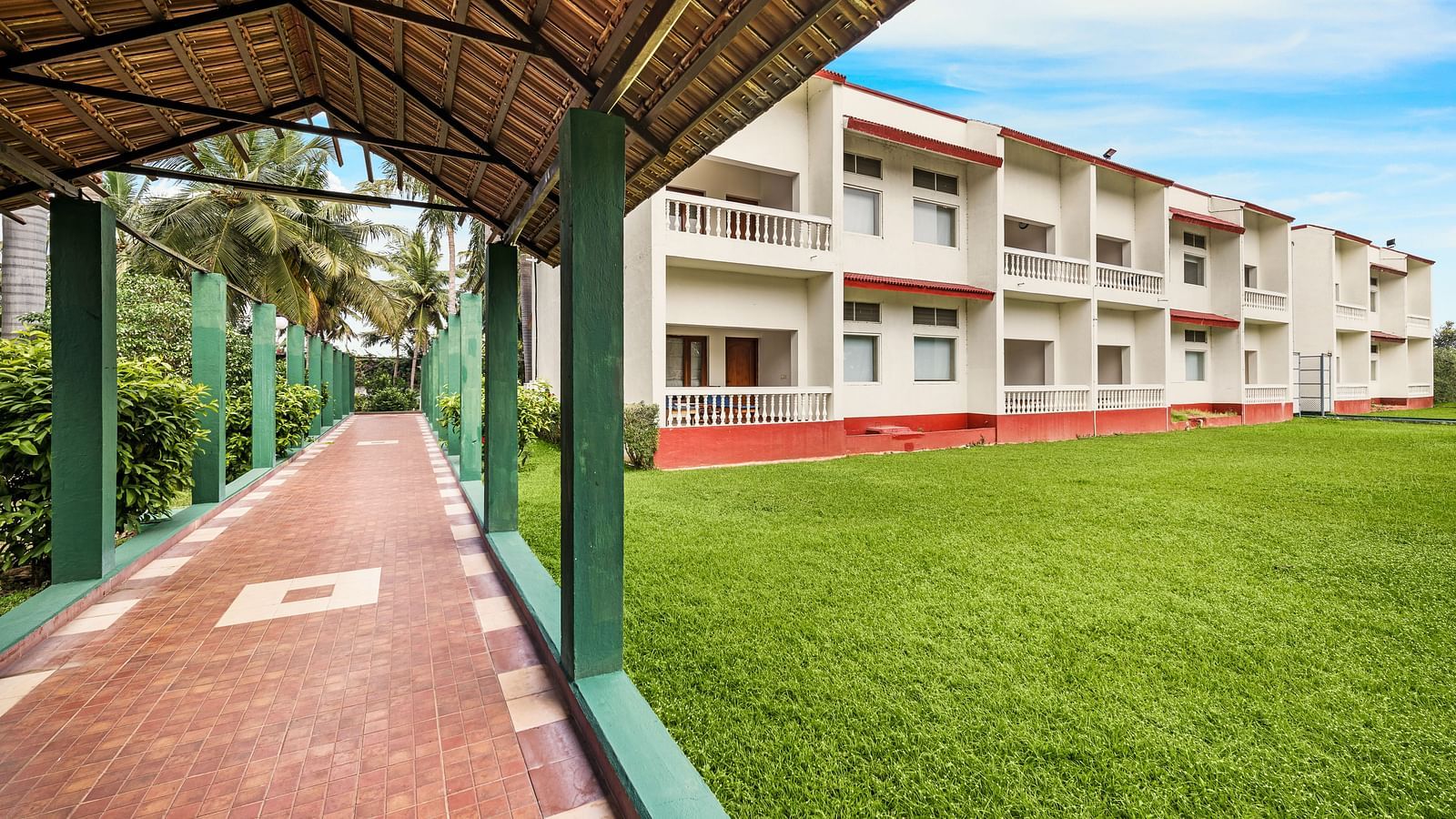 A facade image of the lawn with a shed and the hotel in the background - GReaT Trails River View Resort Thanjavur By GRT Hotels