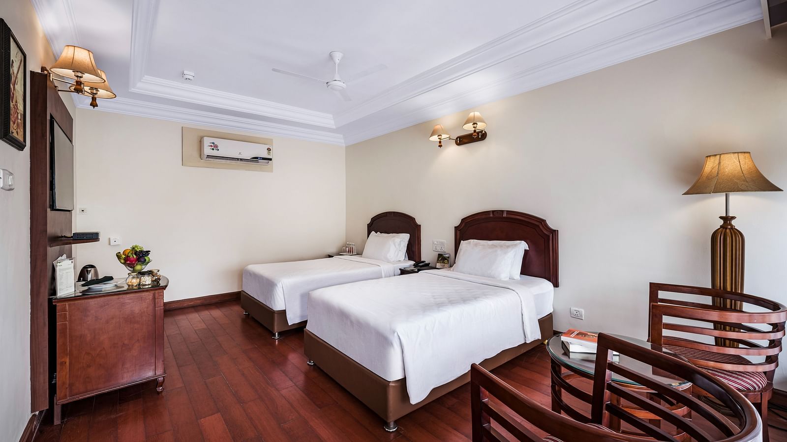 River View Room with balcony featuring two single beds, bed side tables, lamps, flat screen TV, and two chairs - GReaT Trails River View Resort Thanjavur By GRT Hotels