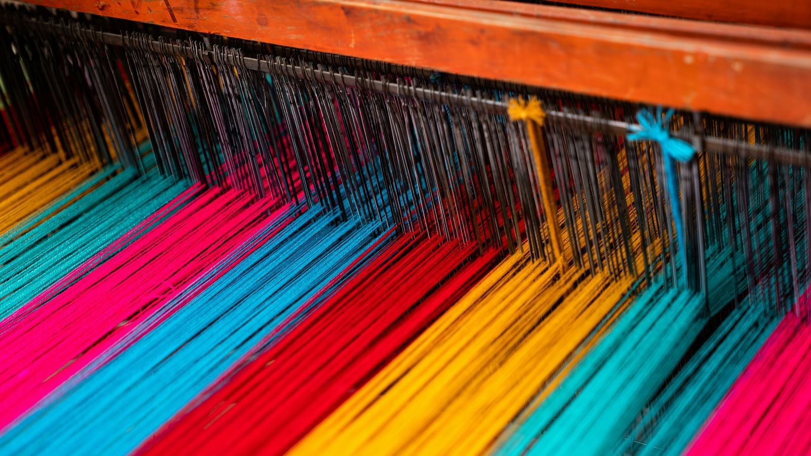 Colourful weaving threads stretched on a loom, creating vibrant patterns.