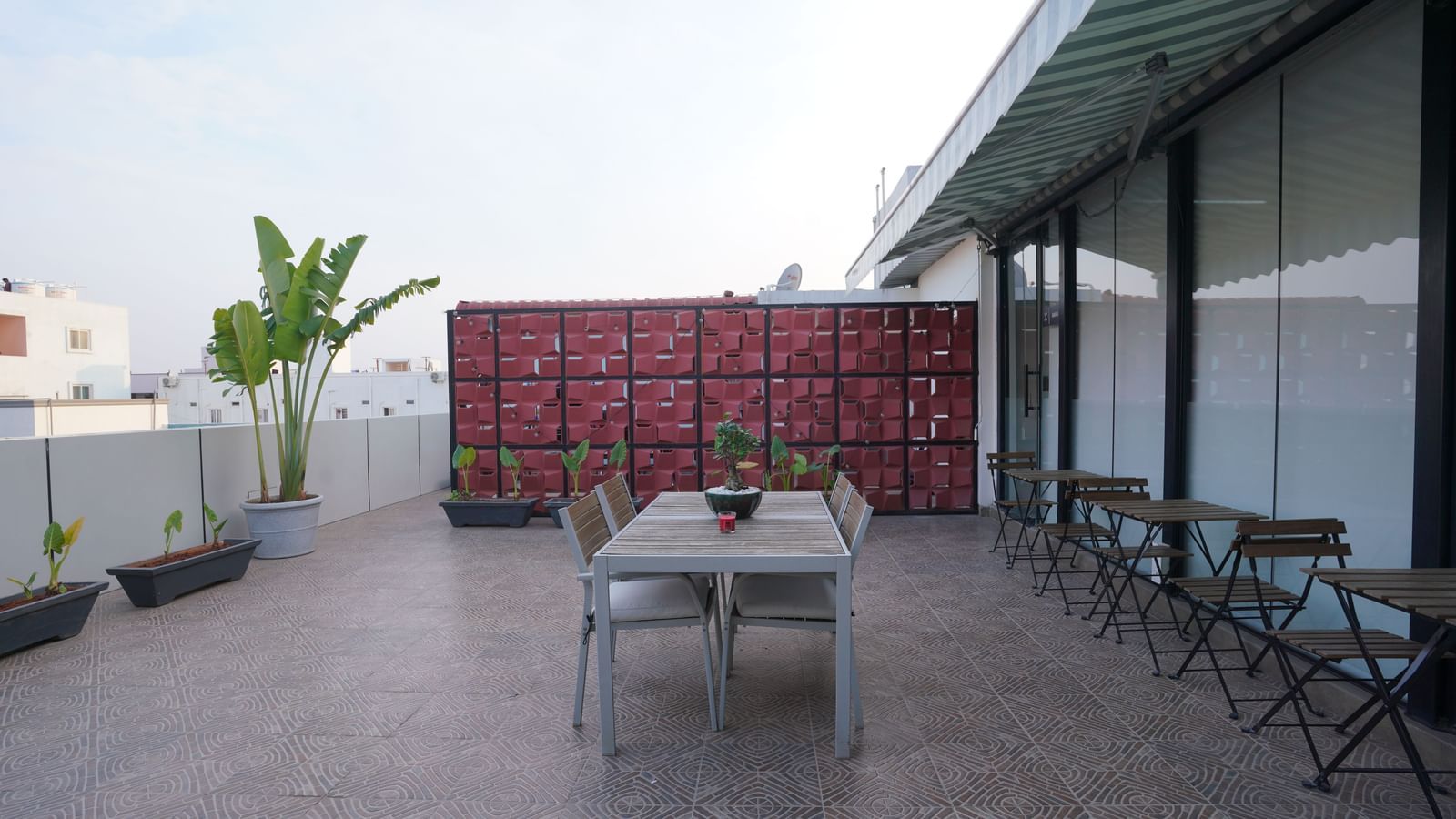 A rooftop dining space with a central table, chairs, and a decorative partition in the background at Hotel Kyzen Smartstays – Smart, Reliable, Kyzen