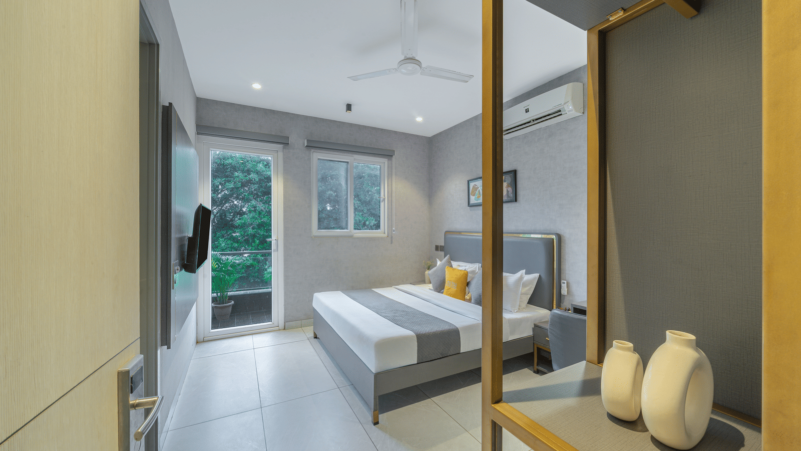 Bedroom of Lime Tree Hotels & Service Apartment Private Limited featuring a full length mirror, decorative vases, and a bed with white linen.