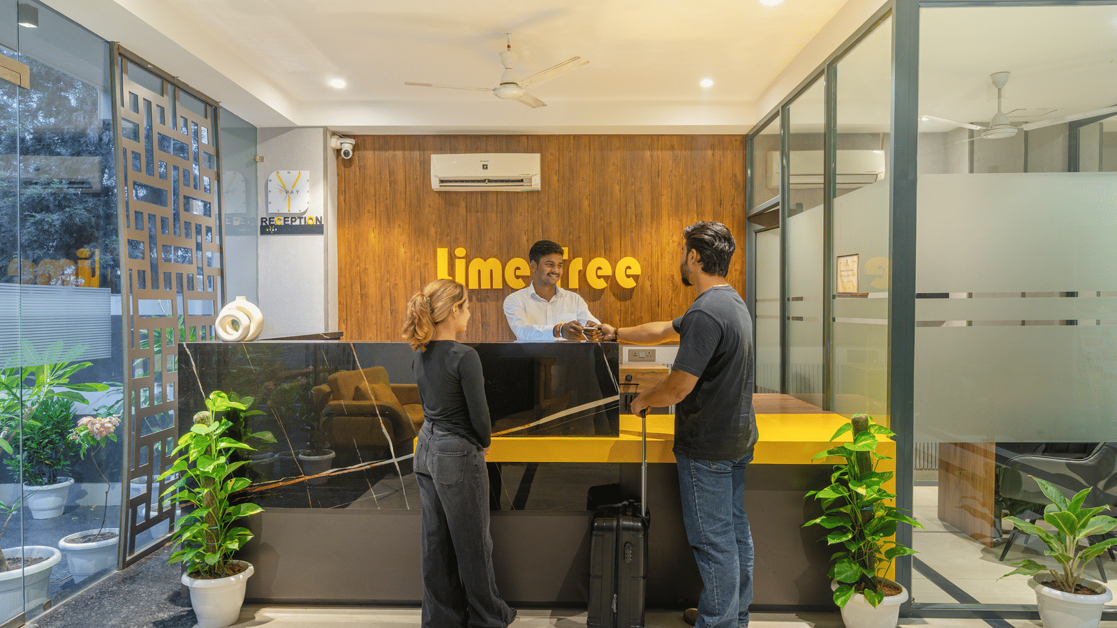 Staff assisting a guest at the reception desk of Lime Tree Hotels & Service Apartment Private Limited.