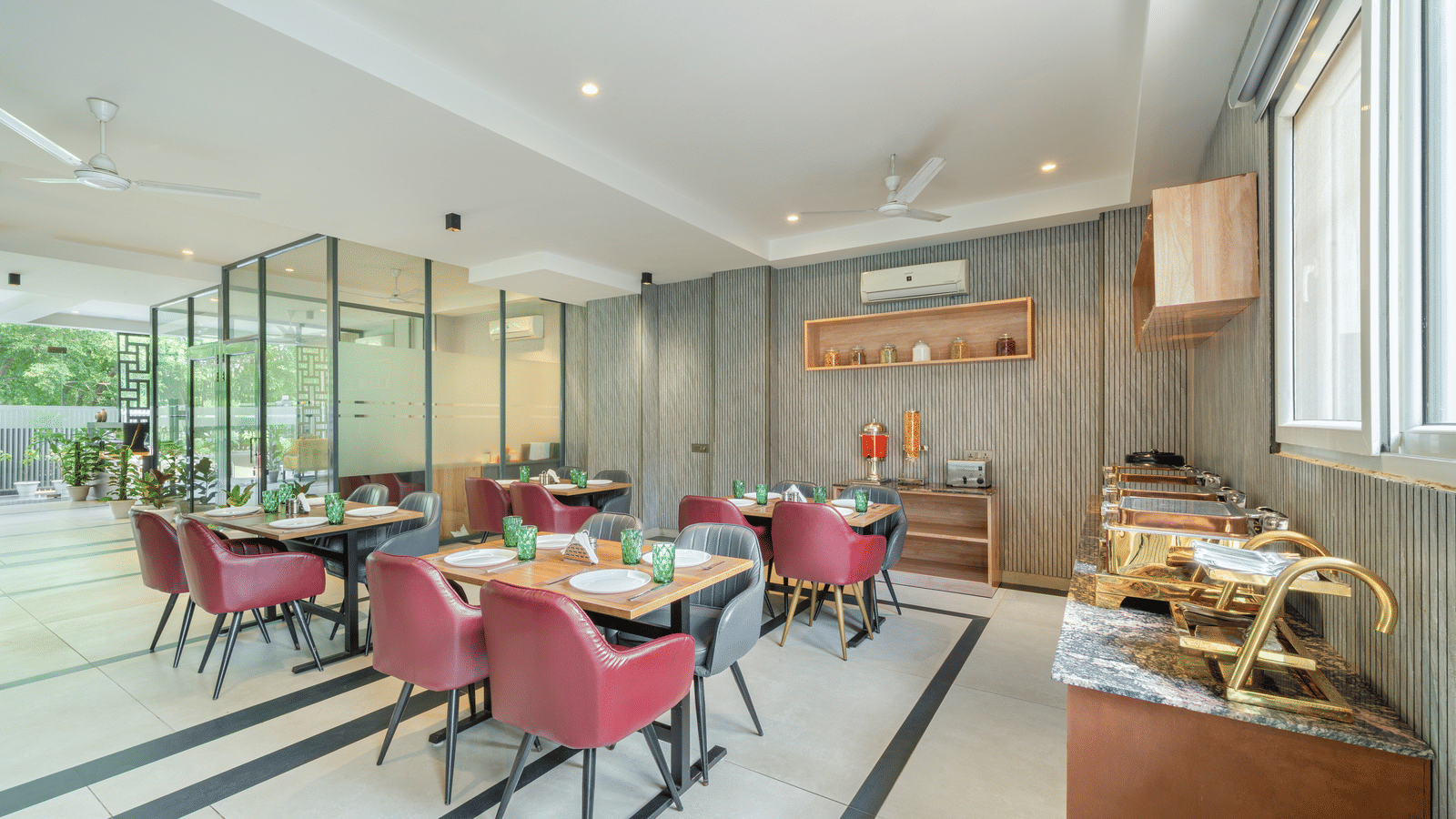 Restaurant of Lime Tree Hotels & Service Apartment Private Limited featuring pink chairs, dining tables, and glass panelled walls.