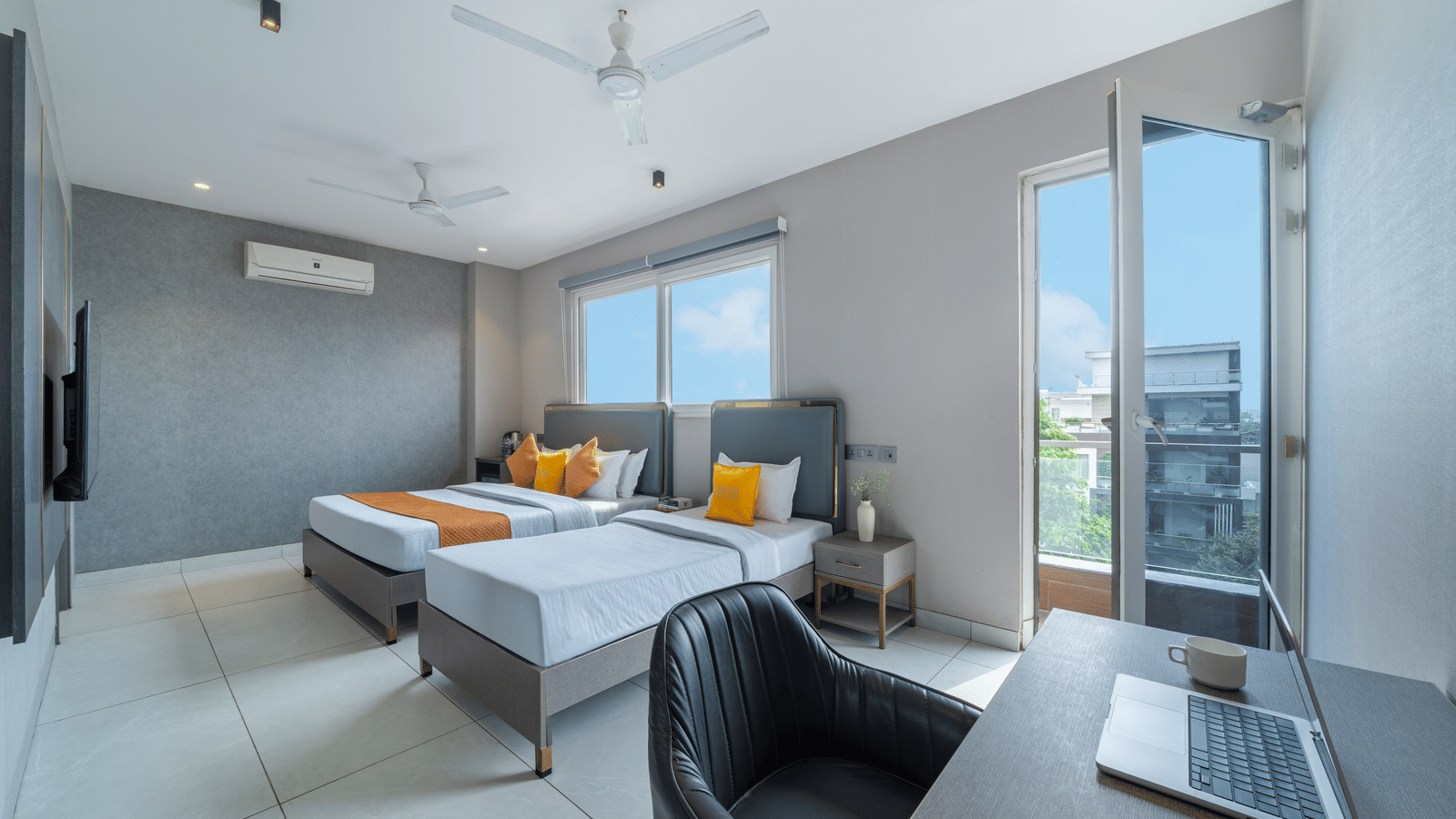 Bedroom of Lime Tree Hotels & Service Apartment Private Limited featuring twin beds, an armchair, and large windows.