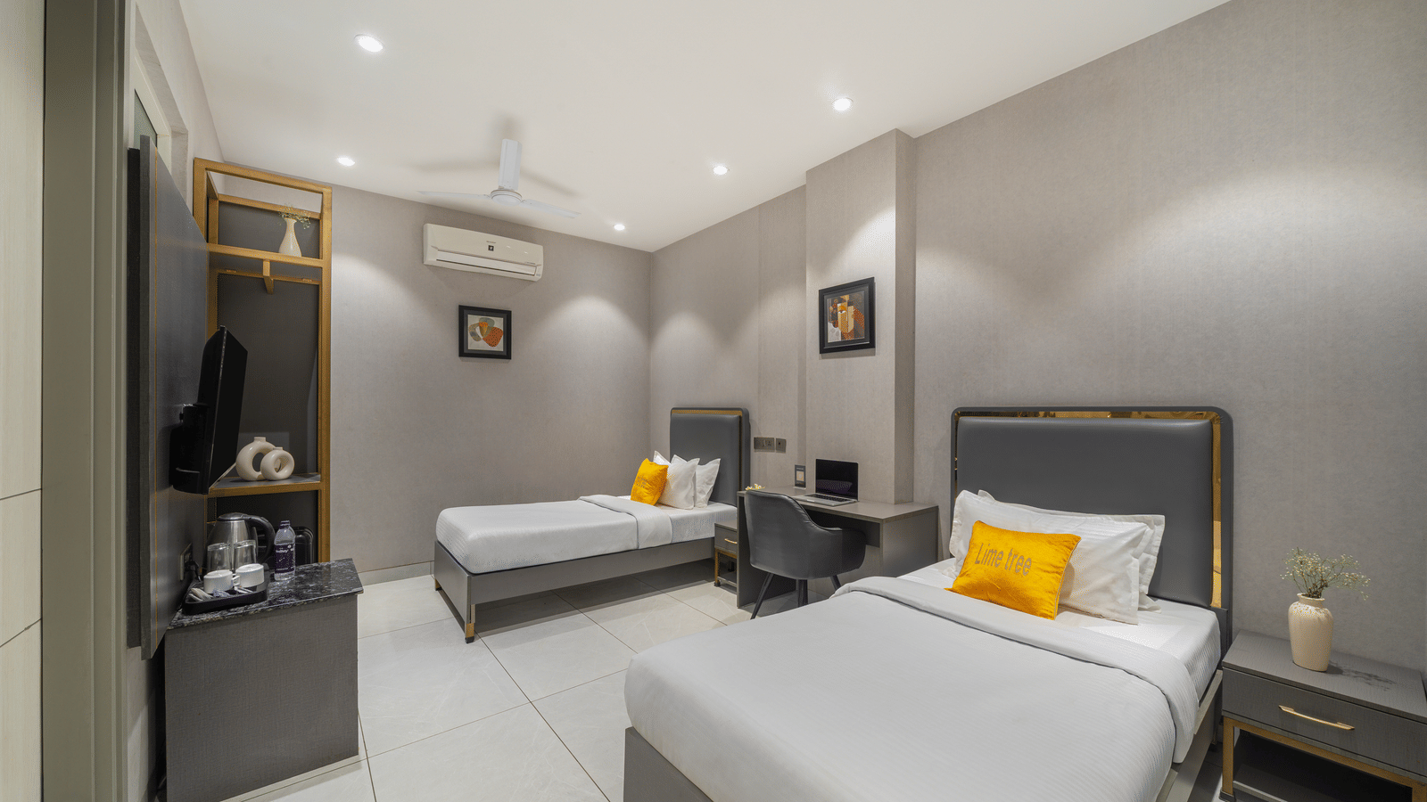 Bedroom of Lime Tree Hotels & Service Apartment Private Limited featuring twin beds with yellow cushions and a grey toned interior.