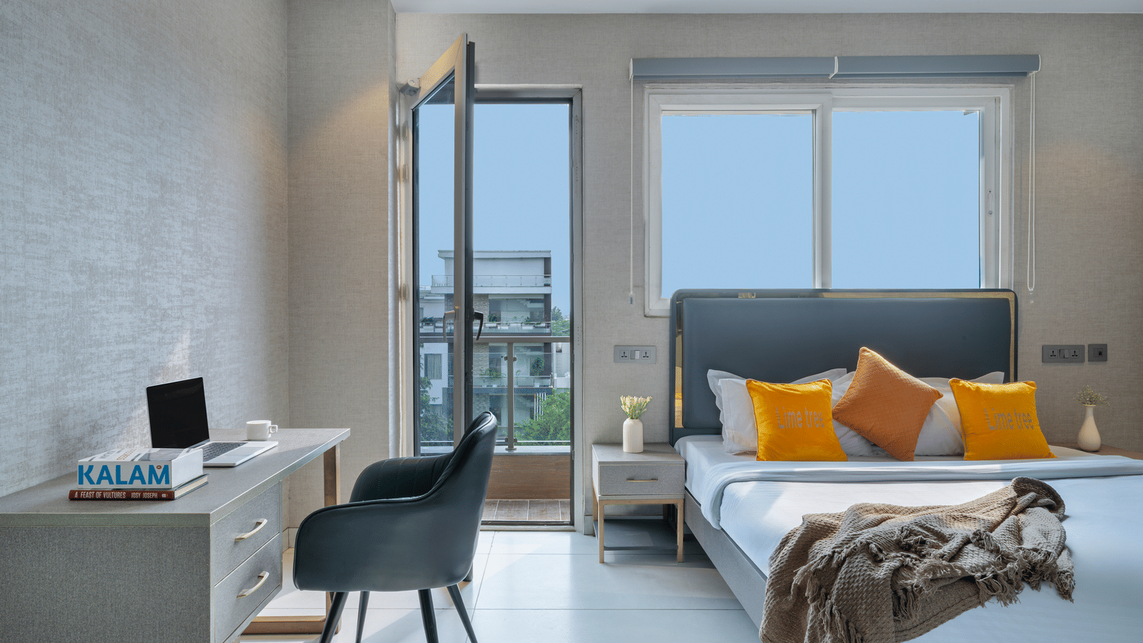 Bedroom of Lime Tree Hotels & Service Apartment Private Limited featuring a writing desk, a chair, and a bed positioned beside a window.