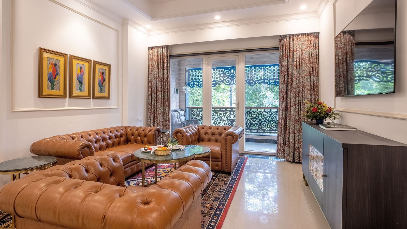 A luxury living area with a sofa set, large glass windows, and a wall-mounted TV at MAYFAIR Palm Beach Resort, Gopalpur-On-Sea