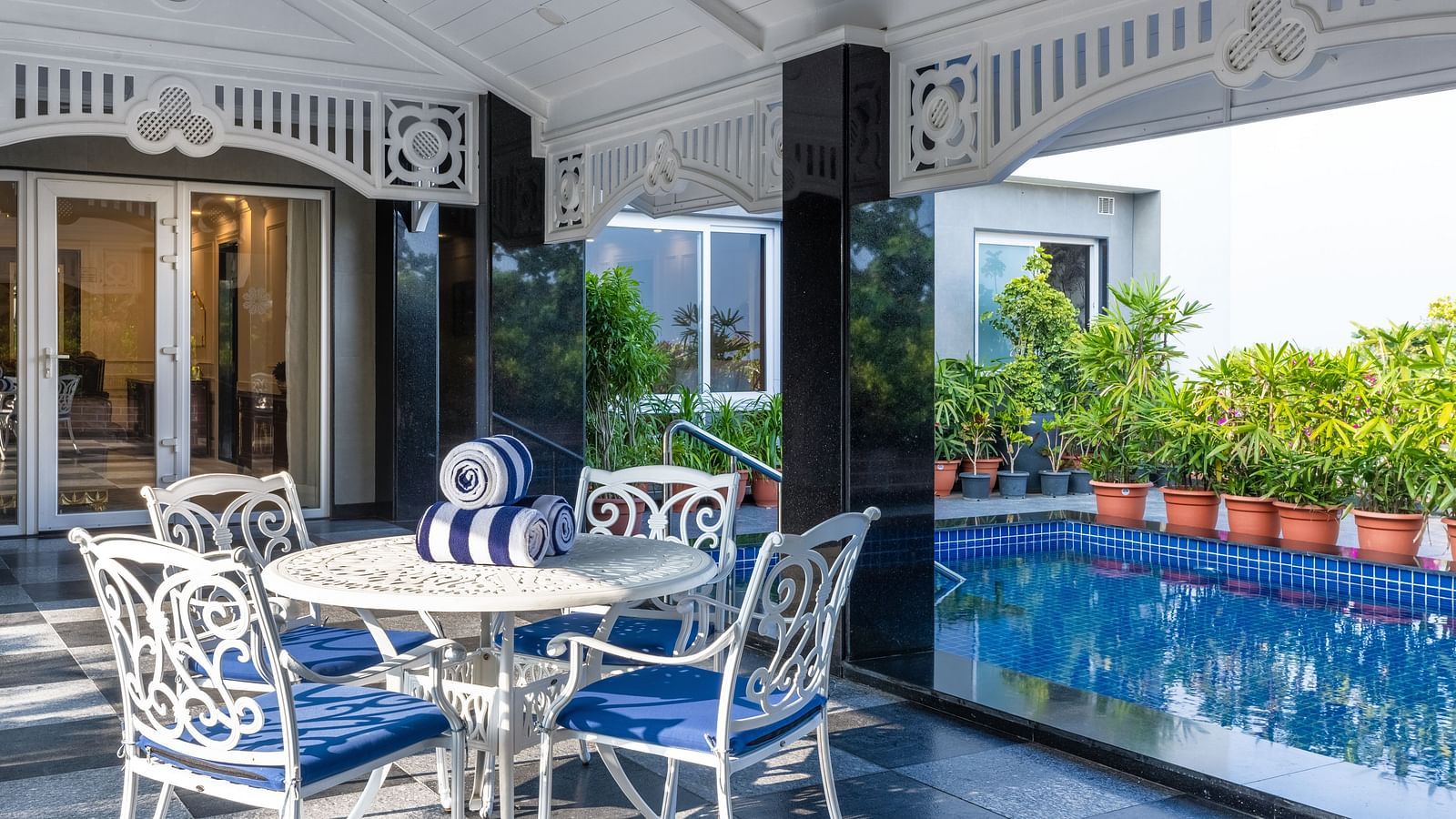 Outdoor seating area by a private pool with vintage white chairs at MAYFAIR Palm Beach Resort, Gopalpur-On-Sea.