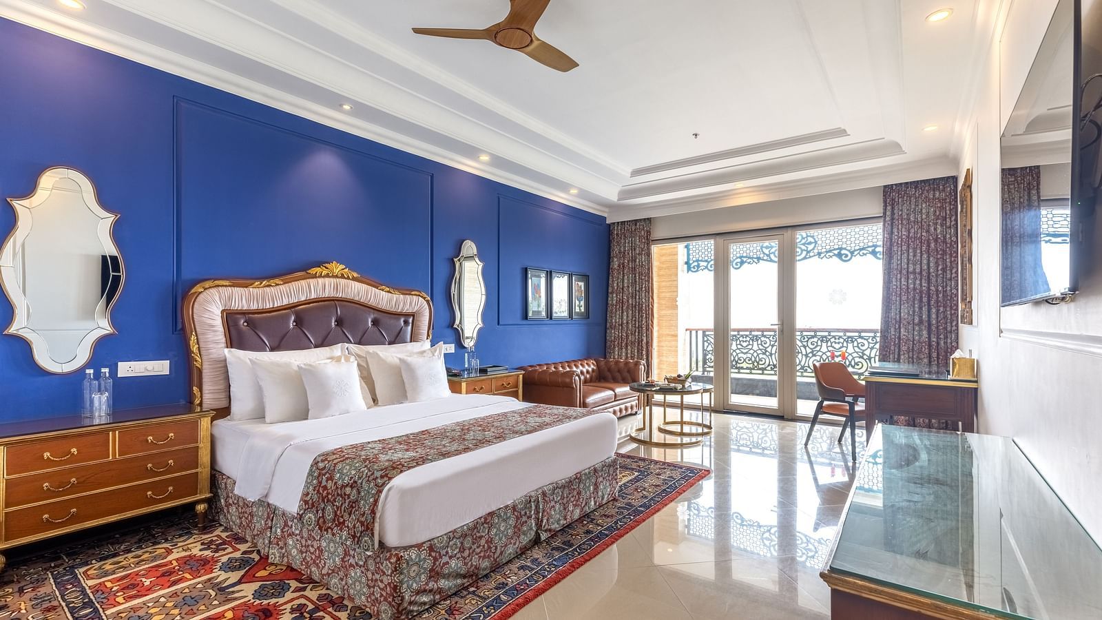 Elegant bedroom with blue accent wall, classic wooden furniture, and sea-facing balcony at MAYFAIR Palm Beach Resort, Gopalpur-On-Sea.