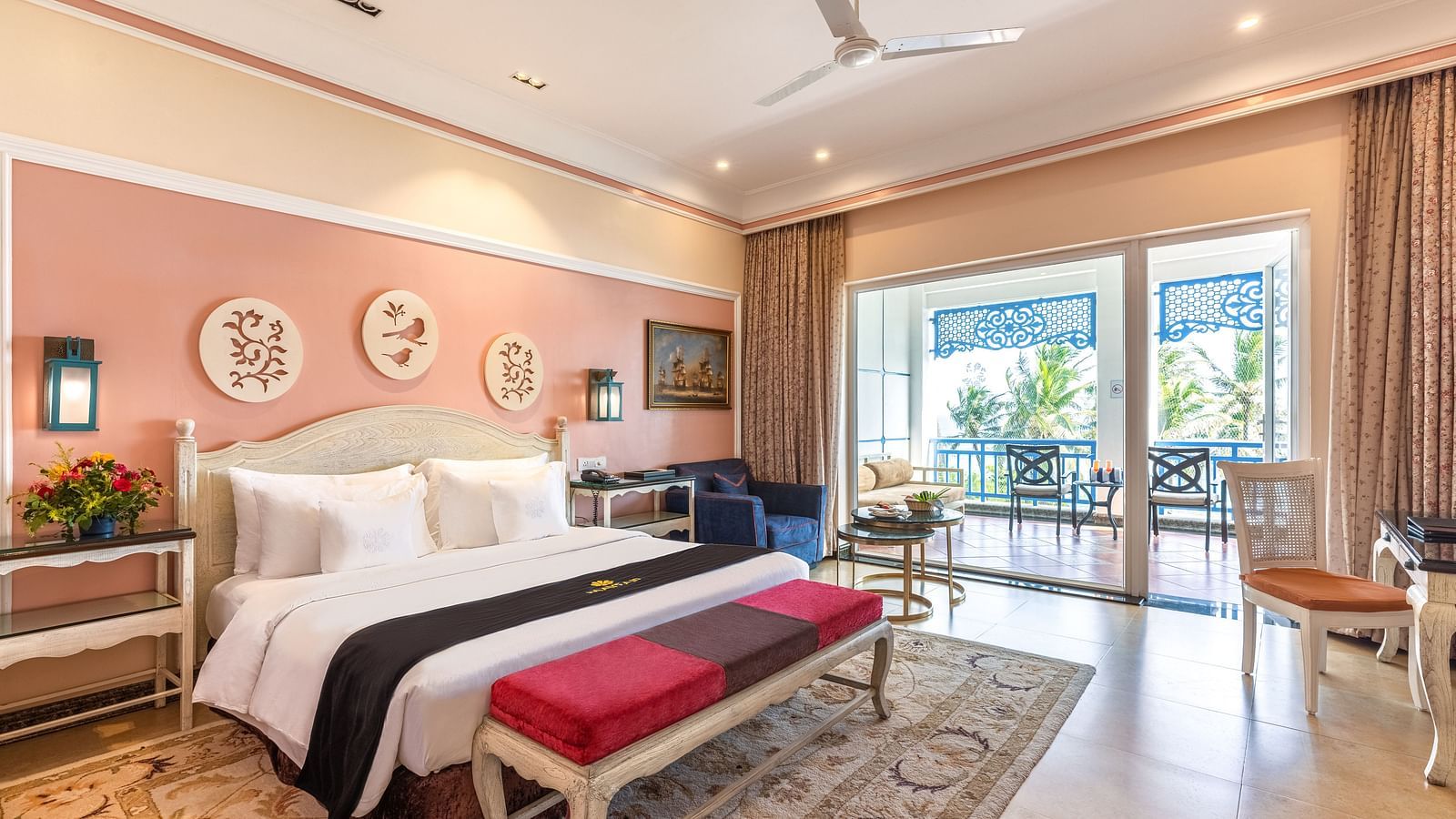 Double bedroom with bedside table, lounge area, a workstation, and large glass windows opening to the balcony at MAYFAIR Palm Beach Resort, Gopalpur-On-Sea