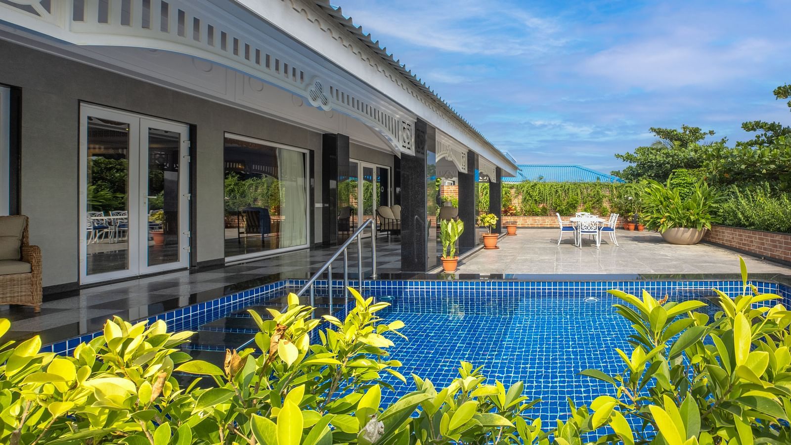 Outdoor swimming pool surrounded by greenery at MAYFAIR Palm Beach Resort, Gopalpur-on-Sea