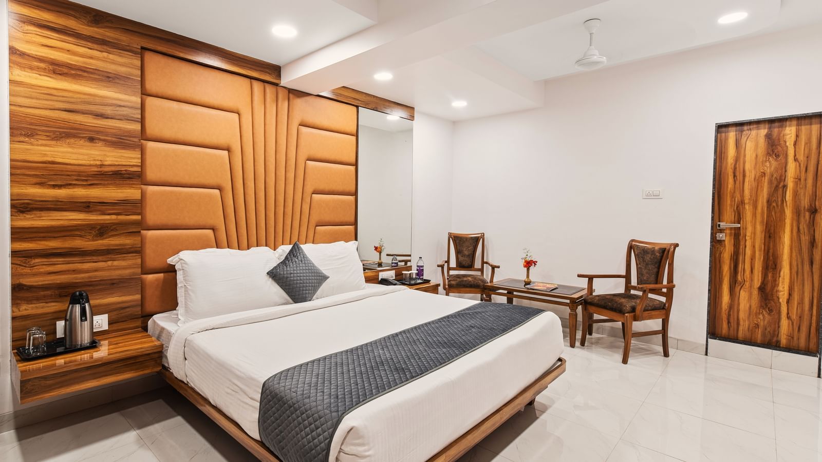 Spacious bedroom at Mayur Retreat featuring a king-size bed, dining table, and modern wooden furnishings.