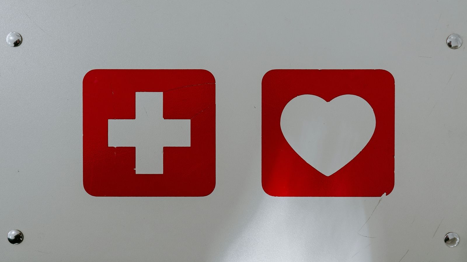 two symbols on a white wall. One is a medicine symbol and another is a heart symbol