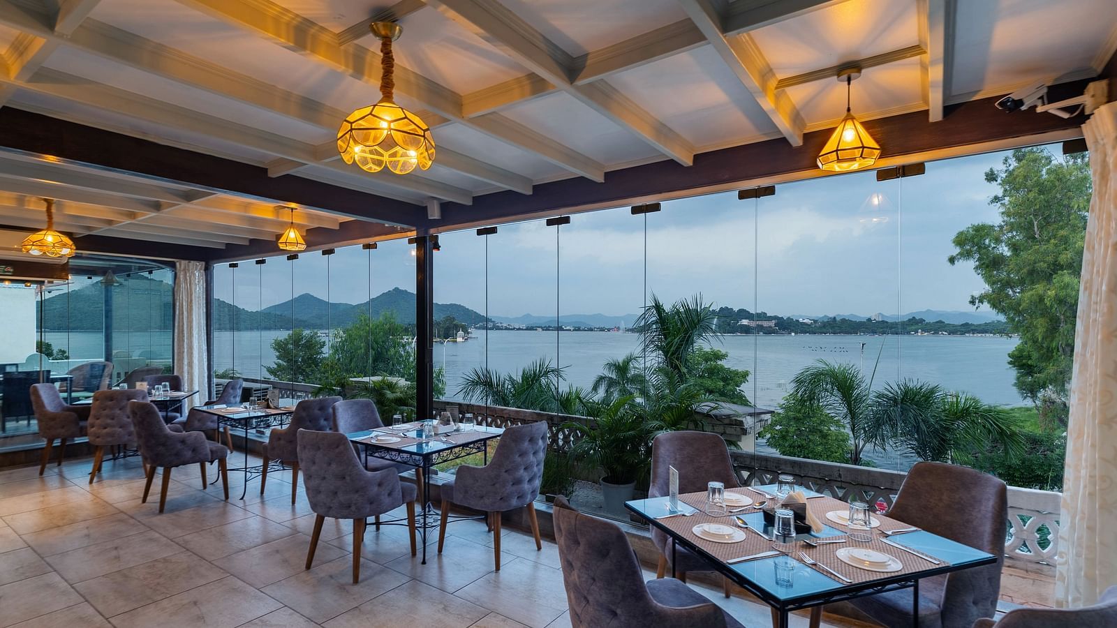 Restaurant area at Panna Vilas Palace includes a four-seater table surrounded by wooden chairs, complemented by warm lighting and potted plants | Panna Vilas Udaipur