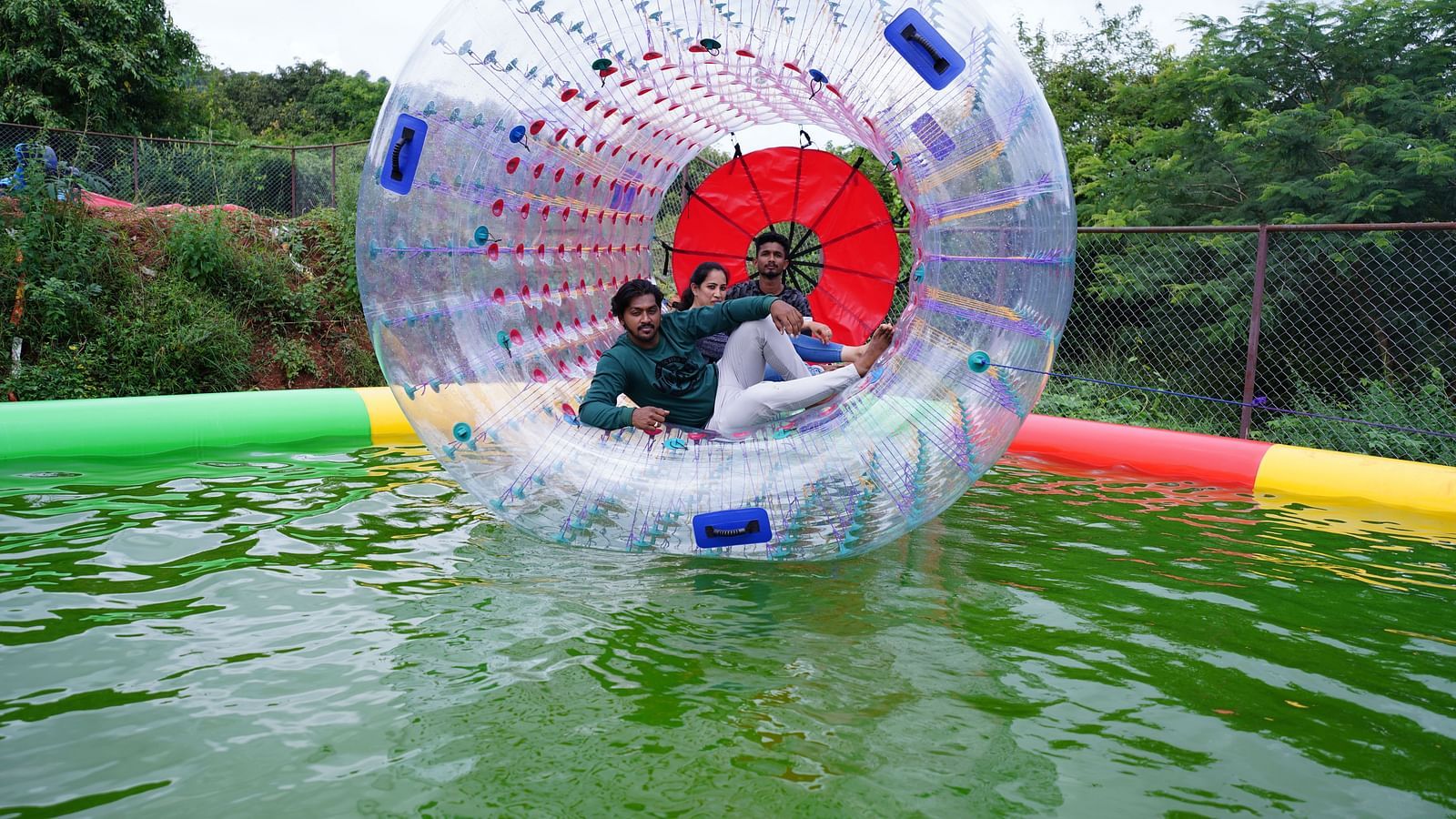 A group of three people enjoying water zorbing at Ravishing Retreat in a mini temporary pool
