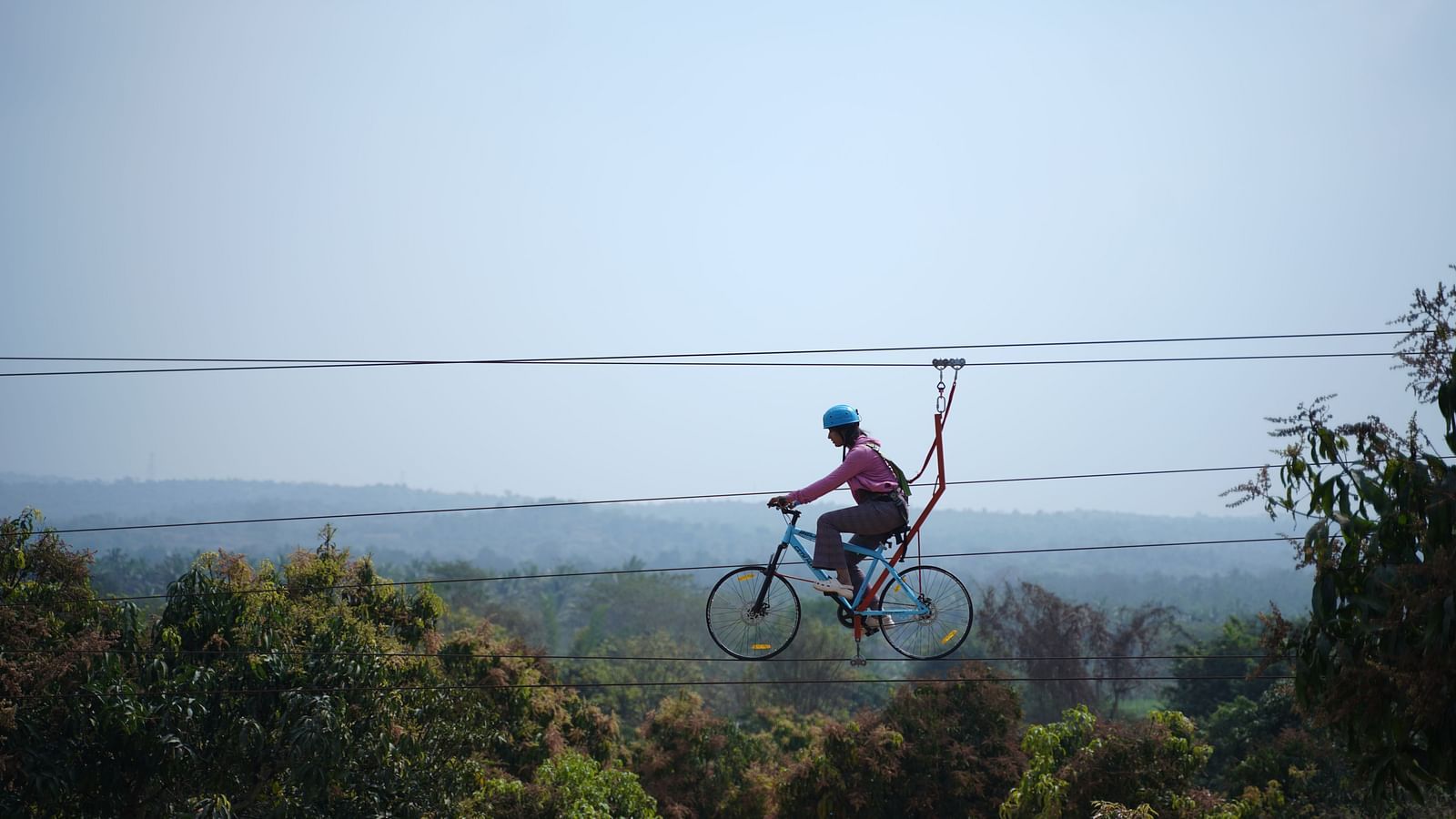 A person on zip cycle at Ravishing Retreat with lush trees in the background