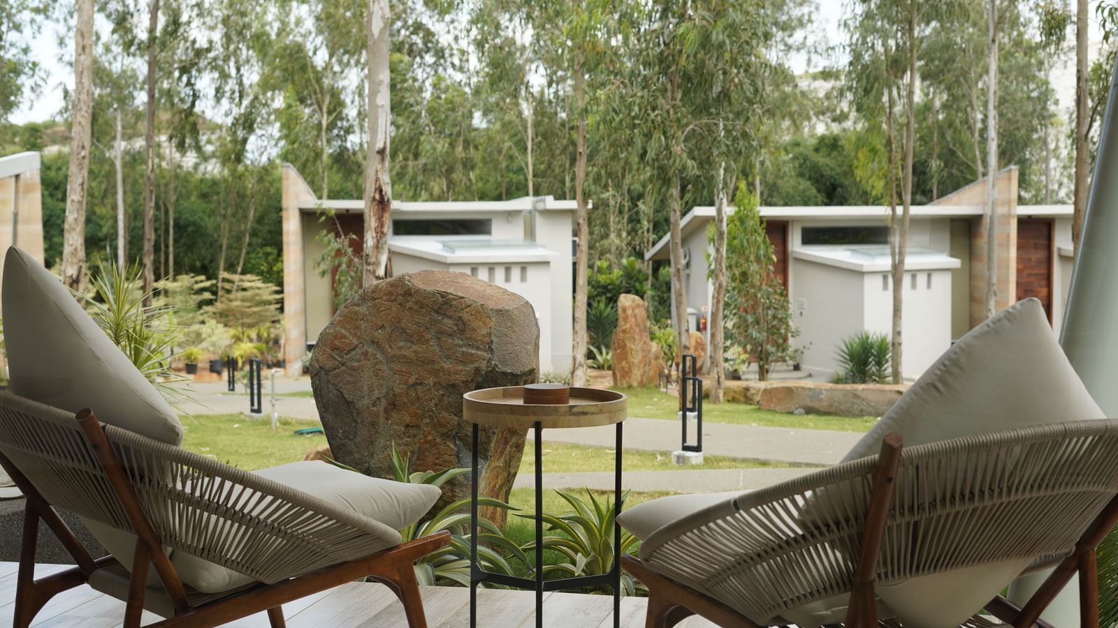 Two bamboo chairs placed on the courtyard of RD's Nature Retreat from where lawn and other room categories can be seen.