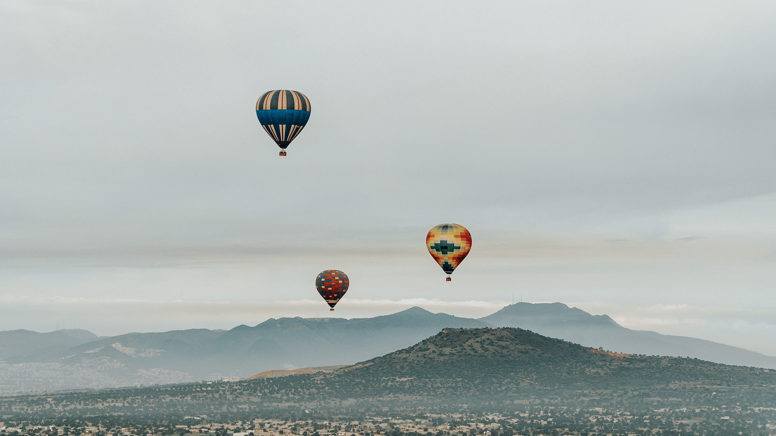 three hot air balloons in the sky with mountain ranges below - couple birthday celebration in Lonavala
