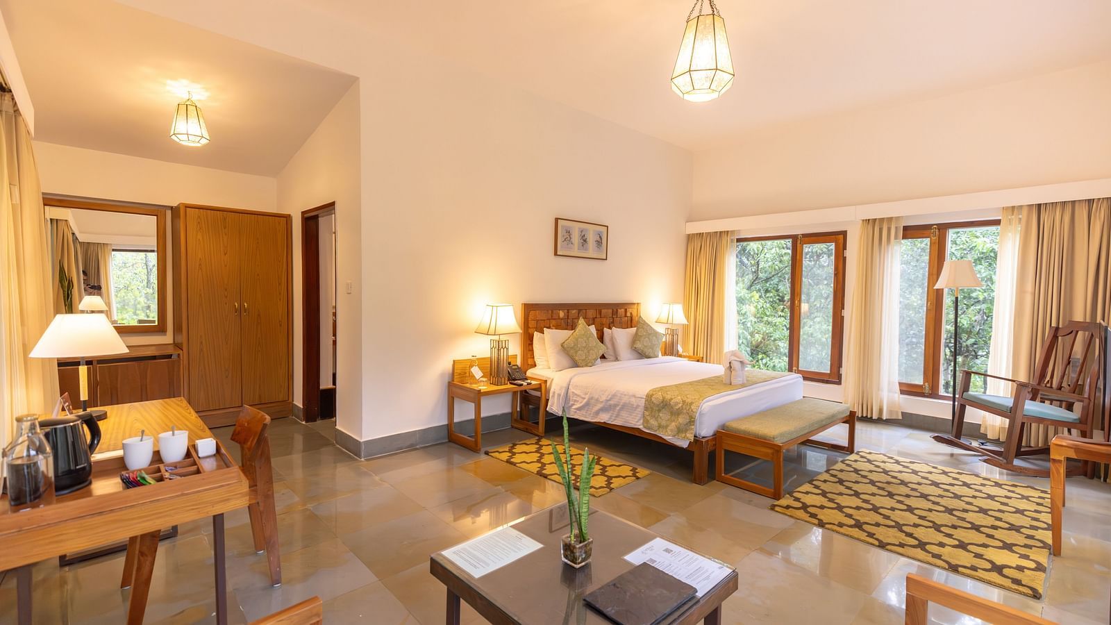 Premium Suite at Saraca Resort & Spa Corbett with a double bed, a sofa chair, a work desk and chair and a chandelier
