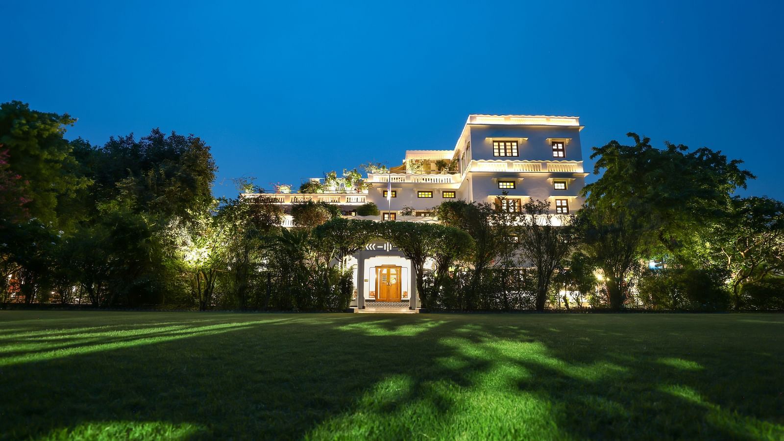 A wide view of the garden area of Saraca Hotel, Lucknow with the hotel building in the background during blue hour