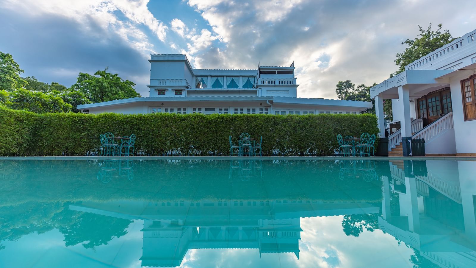 Outdoor swimming pool at Saraca Hotel, Lucknow with the hotel building in the backdrop on a cloudy day