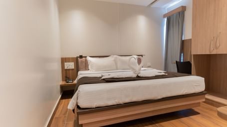 Spacious bedroom with wooden flooring and a comfortable double bed at Beestay Hotels, Rajahmundry.