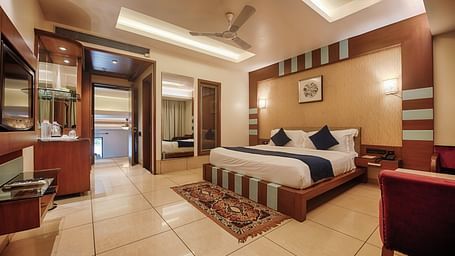Villa at Crescent Resort, Sehore under warm lighting featuring a plush bed facing the wall-mounted TV and a mirror on one side of the bed