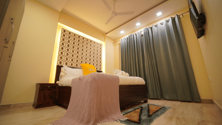 Bedroom of Lime Tree Hotels & Service Apartment Private Limited featuring a canopy draped over the bed and patterned curtains.