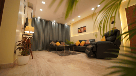 Living room of Lime Tree Hotels & Service Apartment Private Limited featuring black leather sofas, a potted plant, and marble flooring.