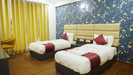 Bedroom of Lime Tree Hotels & Service Apartment Private Limited featuring twin beds, red cushions, and yellow curtains.
