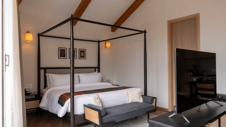  A warm-toned bedroom with wooden beams and plush bedding at Nivasana Manali.