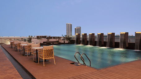 Rooftop swimming pool with outdoor seating at Ramada Encore by Wyndham Gurugram Dwarka Expressway, providing a comfortable space to unwind.