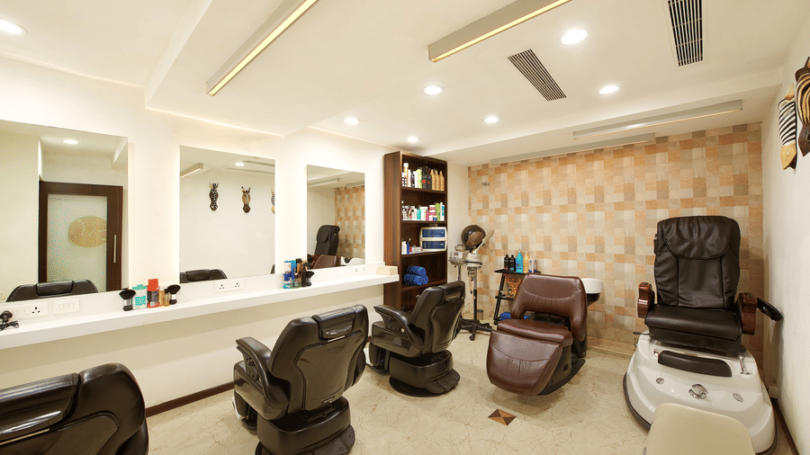 A salon with several chairs, a huge mirror on the wall, and shelves full of beauty products - Accord Hotels and Resorts