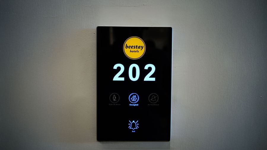 A screen against a wall with room number  and bell being displayed on it - Beestay Hotels Financial District, Hyderabad 