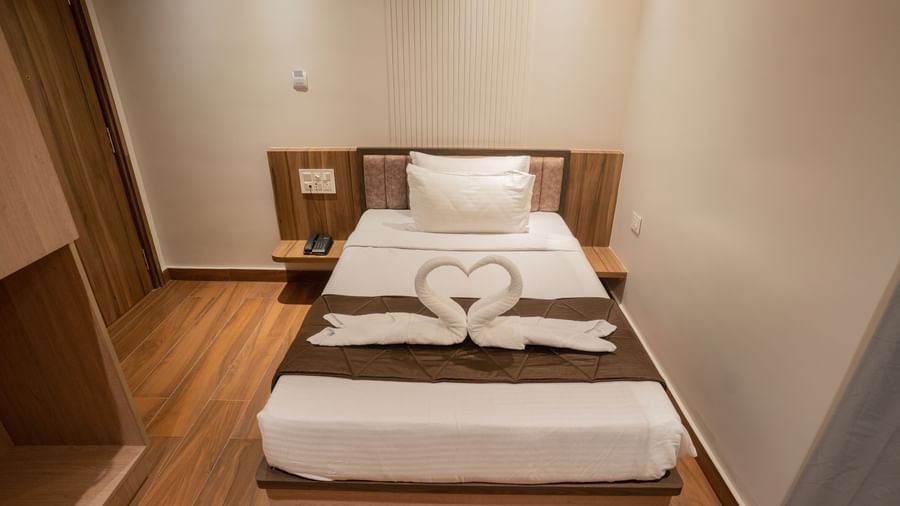 Single bed with crisp linen and towel swan decoration creating a warm ambience at Beestay Hotels, Rajahmundry.