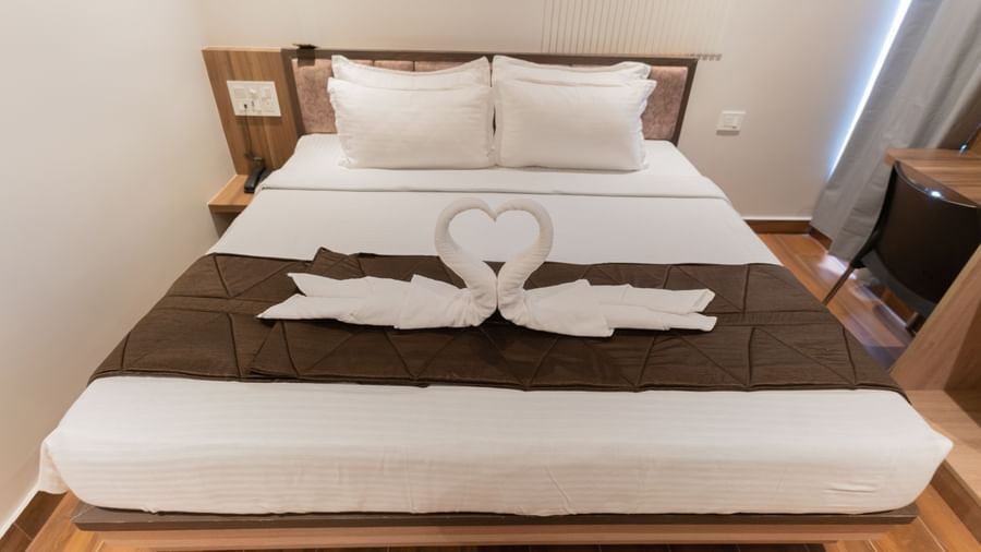 View of a spacious bed with neatly arranged swan decorations made from towels at Beestay Hotels, Rajahmundry.