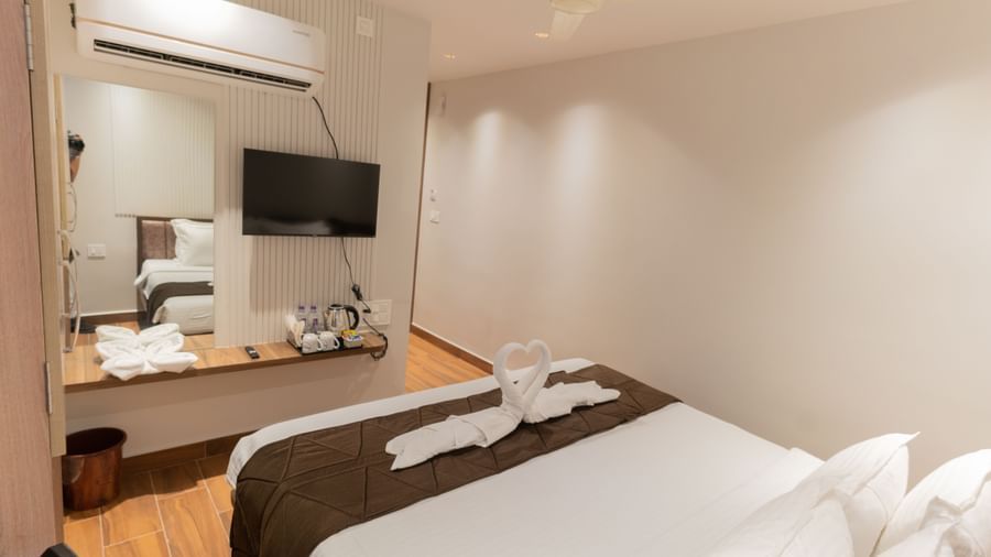 Modern bedroom with double bed, TV, and work desk featuring minimal decor at Beestay Hotels, Rajahmundry.