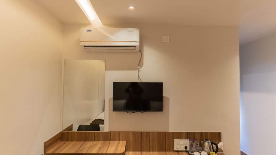 Bedroom view with a desk, wall-mounted TV, and air-conditioning at Beestay Hotels, Rajahmundry.