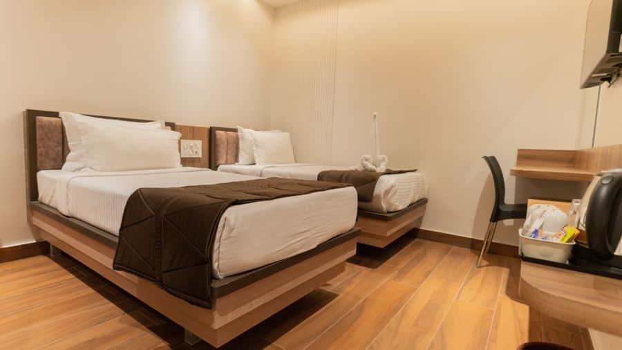 Spacious twin beds with bedside table in a cosy guest room at Beestay Hotels, Rajahmundry.