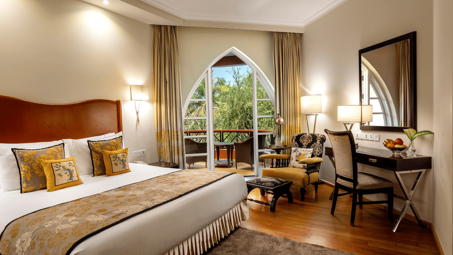 a double bed with a study table and lamps inside Deluxe Suite - Caravela Beach Resort Goa