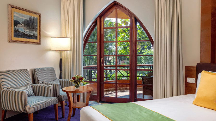 a double bed, sofas and a small table inside Superior Room - Caravela Beach Resort Goa