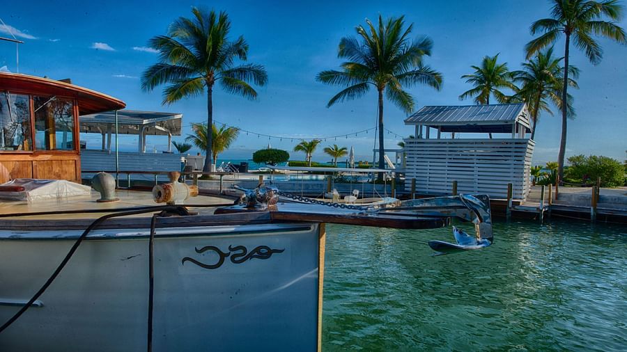 View of Casa Morada's waterfront with a docked boat, palm trees, and resort buildings in the background.