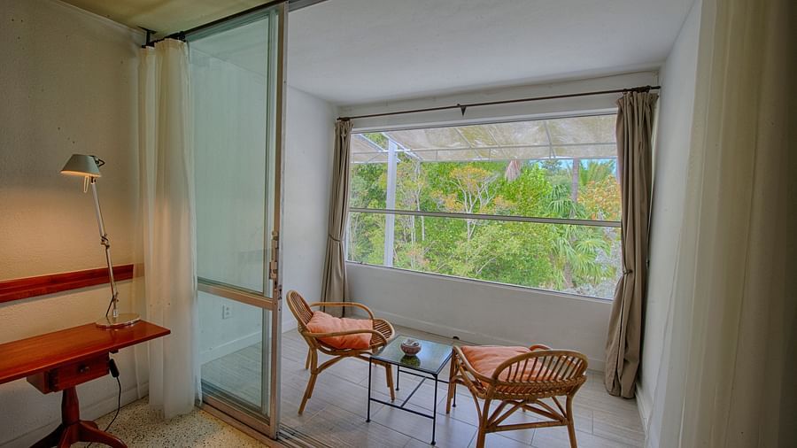 Room at Casa Morada with a desk, two chairs, and a large window overlooking greenery.