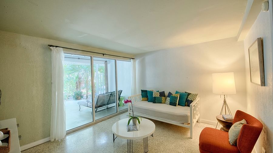 Sitting area at Casa Morada with a sofa, armchair, and coffee table next to a sliding glass door.