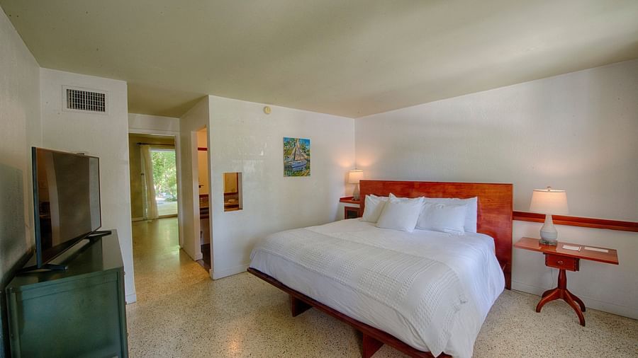 Casa Morada's bedroom with a king bed, wooden headboard, wall art, and a TV.