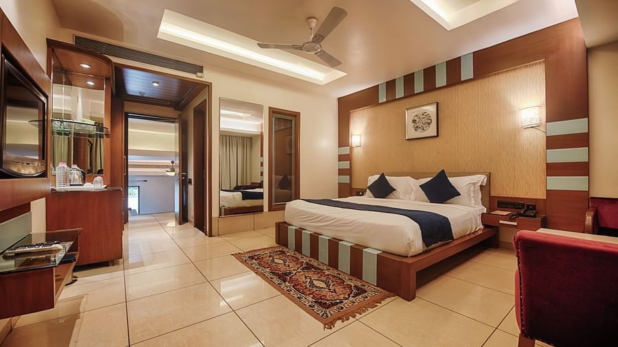 Villa at Crescent Resort, Sehore under warm lighting featuring a plush bed facing the wall-mounted TV and a mirror on one side of the bed