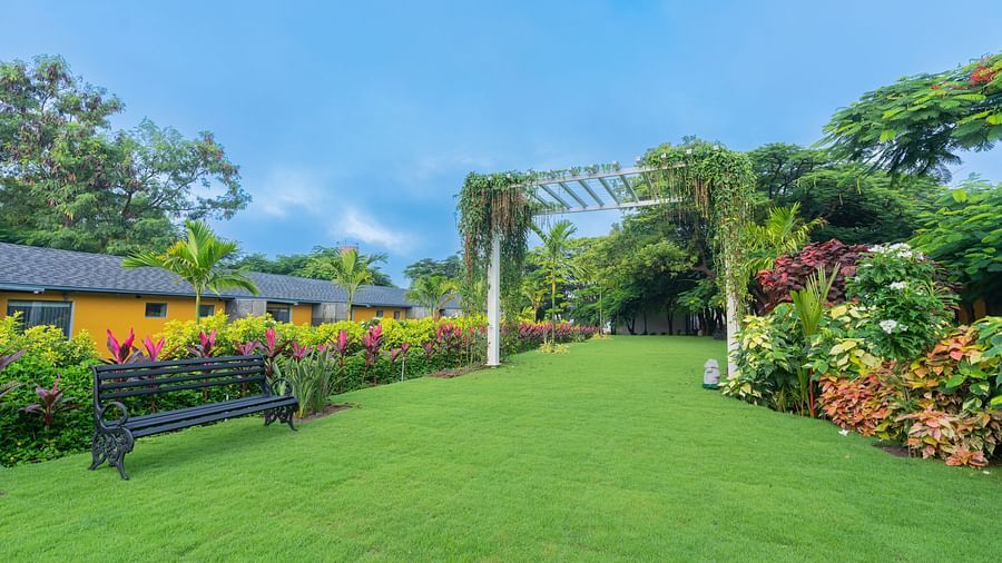 full view image of a lawn with premium room villas in the background featuring a wooden bench in the lawn - Darza Resorts